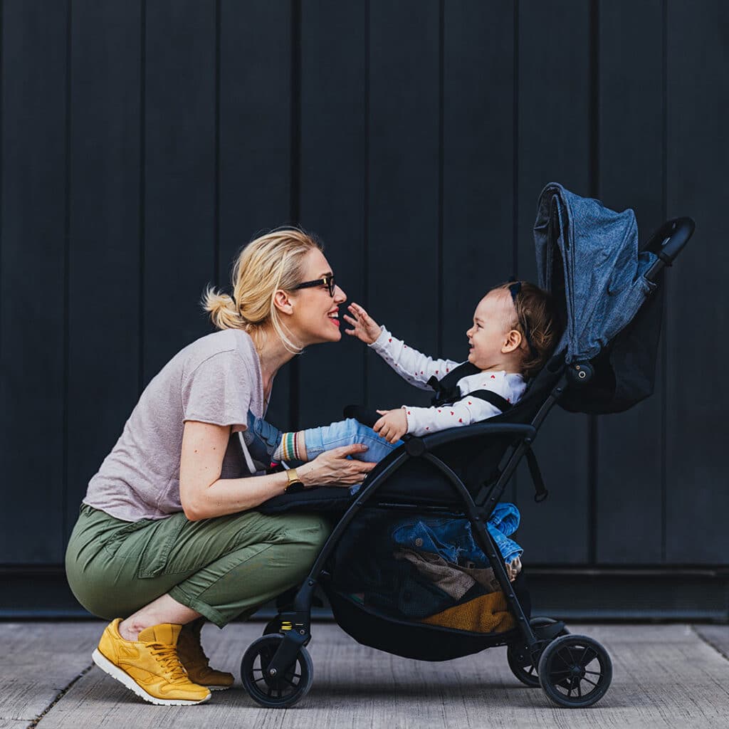 Young mother smiling at baby in stroller