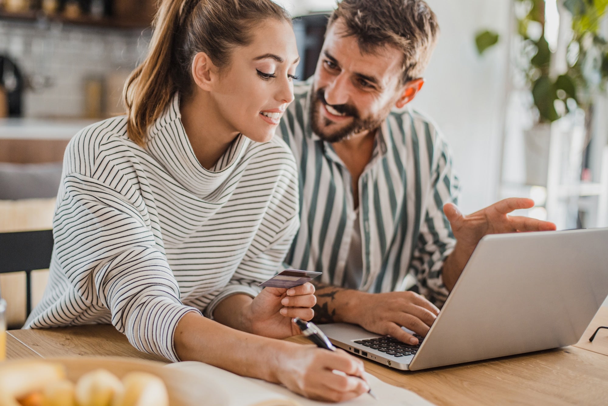 Smiling couple looking at a laptop and notes