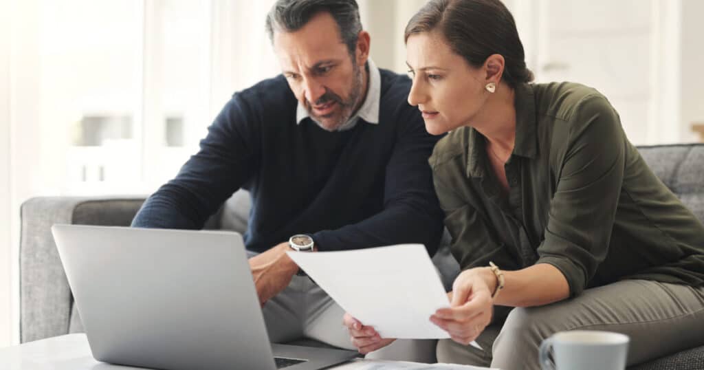 Mature couple reviewing financial documents and retirement planning information together at home after leaving Federal service.