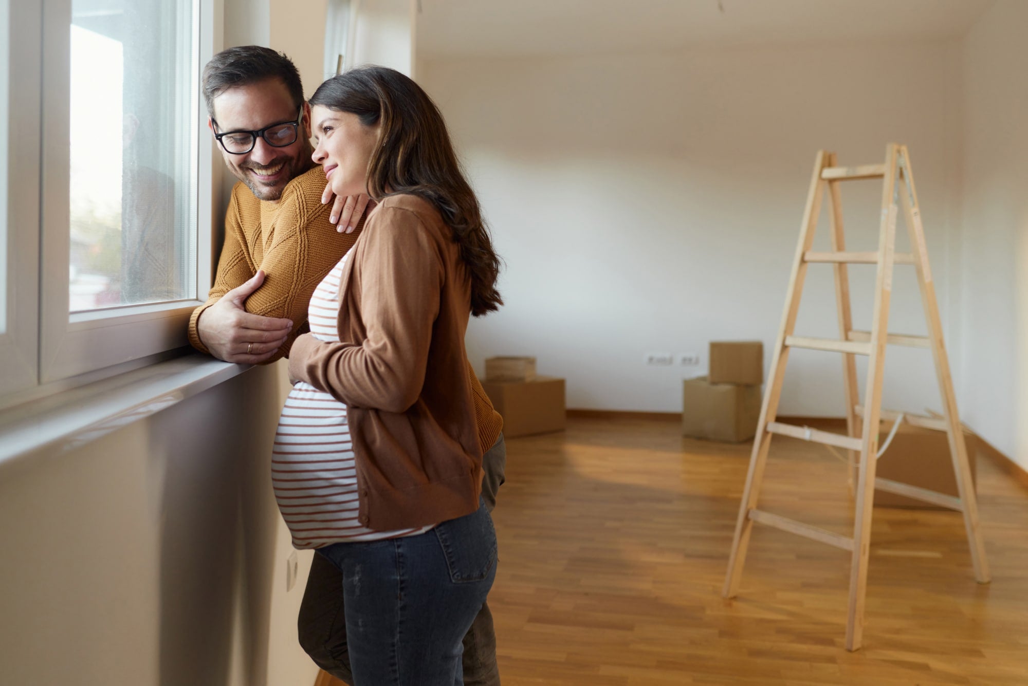 Couple expecting a baby in a new home, representing a qualifying life event and the need to update benefits and financial plans