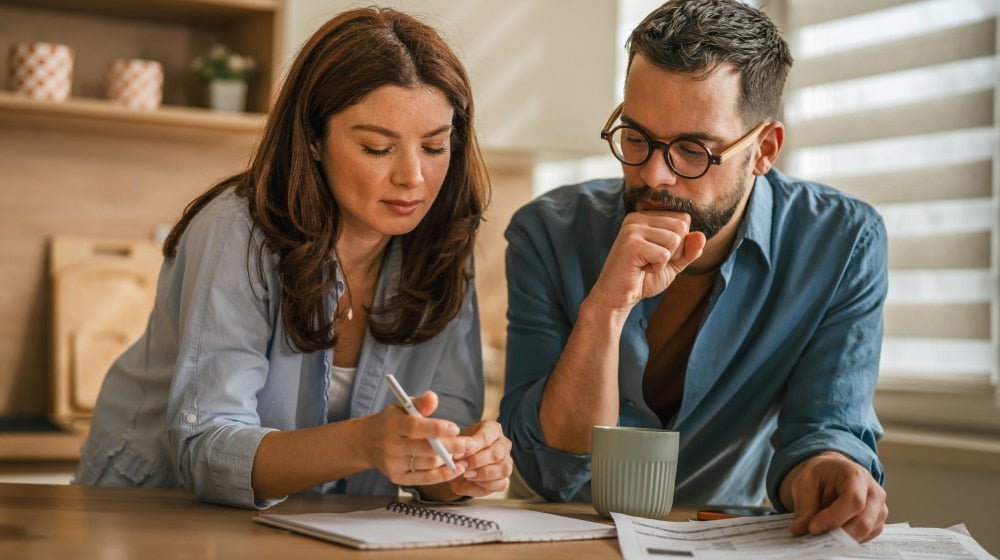 Couple reviewing household finances and insurance documents together while planning long-term financial protection and benefits coverage.
