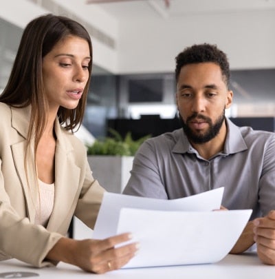 Young professional reviewing and explaining a document to a coworker during an office meeting.