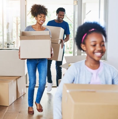 Federal employee family moving into a new home, carrying boxes during a relocation.