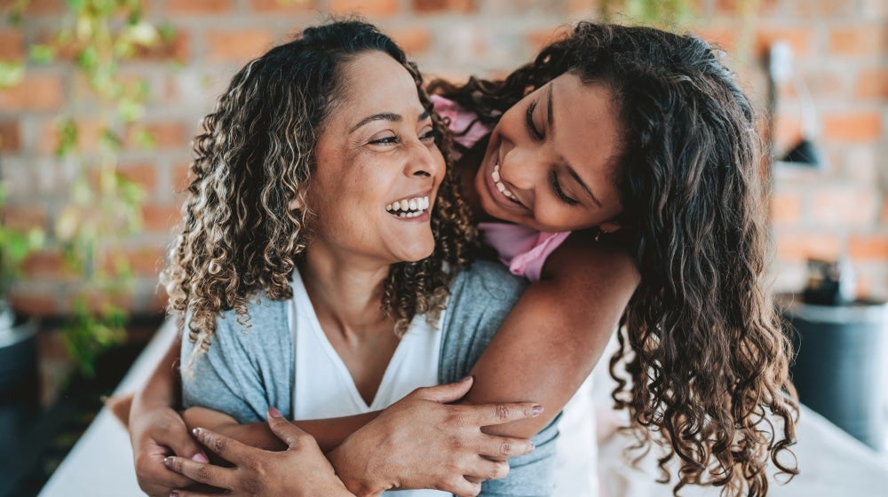 Mother daughter embracing and smiling, representing emotional care of single parents.