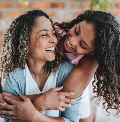 Mother daughter embracing and smiling, representing emotional care of single parents.